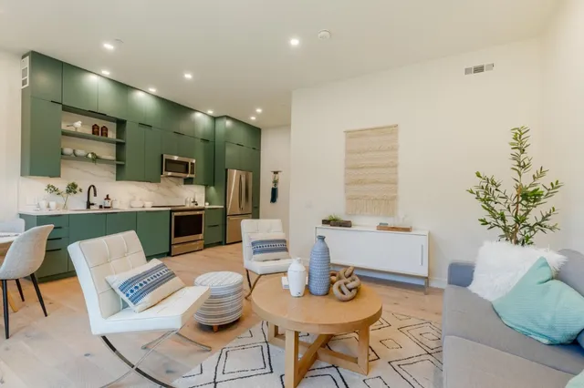 a living room with furniture kitchen view and a large window