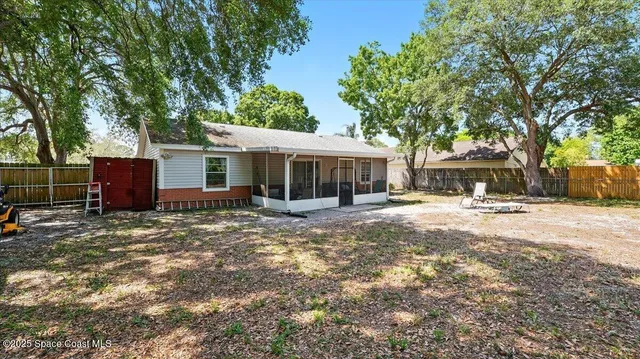 a view of a house with a yard and large tree