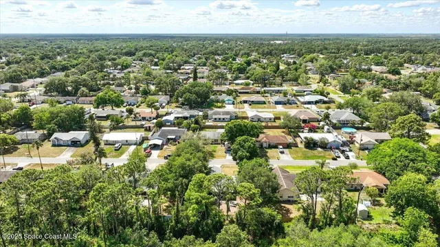 an aerial view of residential houses with outdoor space and trees