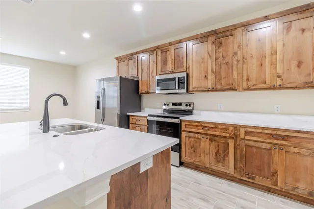 a kitchen with stainless steel appliances kitchen island granite countertop a stove a sink and a microwave