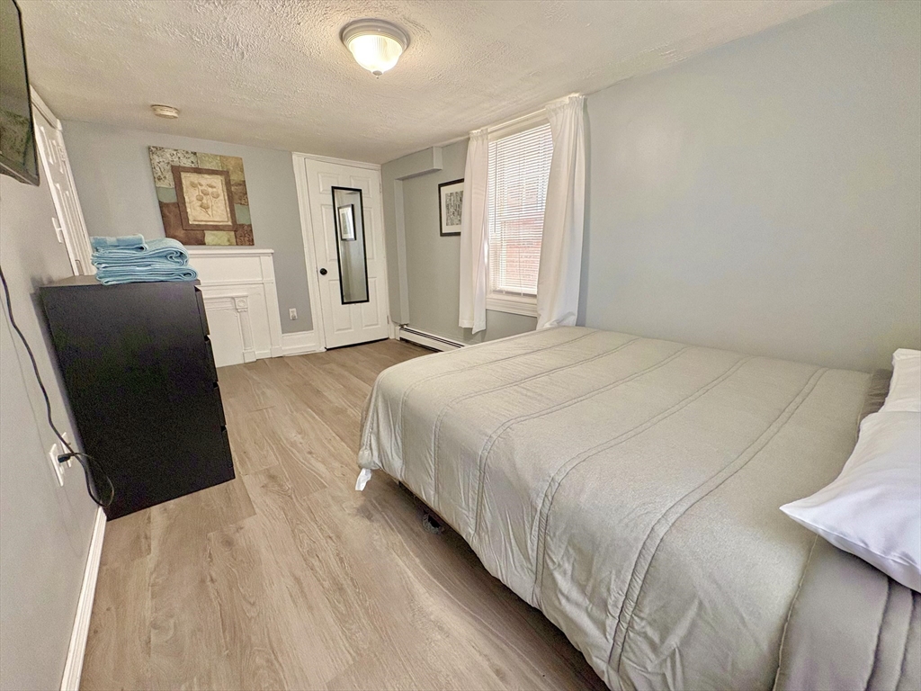 285 Roxbury Street Boston, MA 02119 - Photo 11 of 15 a spacious bedroom with a bed and wooden floor