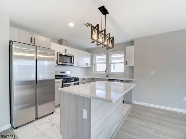 a kitchen with kitchen island a counter top space stainless steel appliances and a chandelier