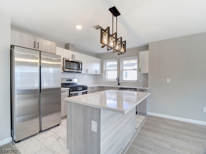 32 North 14th Street, Unit 2 Newark, NJ 07107 - Photo 5 of 14 a kitchen with kitchen island a counter top space stainless steel appliances and a chandelier