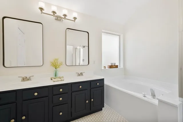 a bathroom with a tub sink double vanity and mirror
