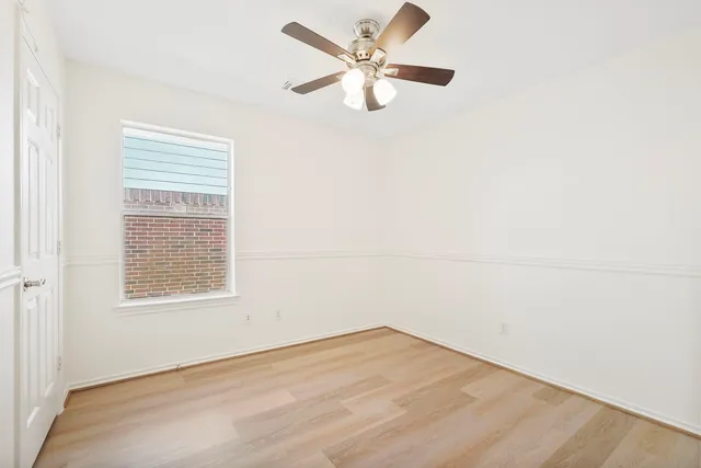 an empty room with a window and a fan