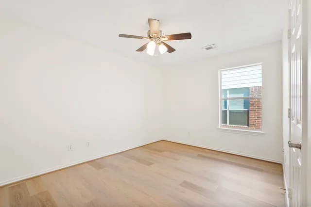 an empty room with a window and a fan