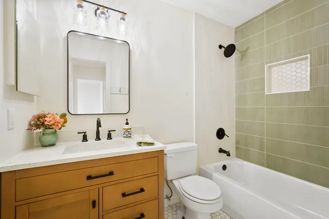 a bathroom with a toilet a sink a mirror a bathtub and shower