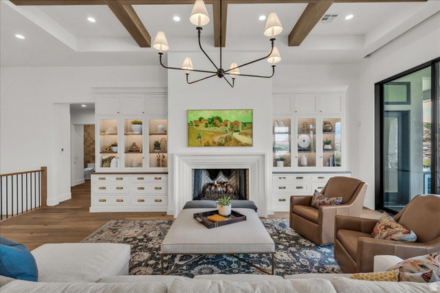 2608 Canyon Ridge Drive St. George, UT 84770 - Photo 14 of 86 Spacious living area featuring exposed wood ceiling beams, a decorative fireplace with a mantel, built-in cabinetry with glass-front uppers and solid lower drawers, and large format windows