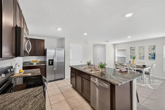 a kitchen with a stove a sink a microwave a dining table and chairs