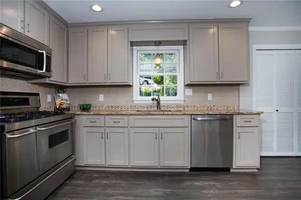 a kitchen with stainless steel appliances granite countertop a stove a sink and a microwave