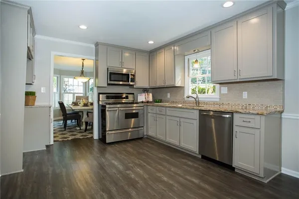 a kitchen with granite countertop a sink cabinets and stainless steel appliances