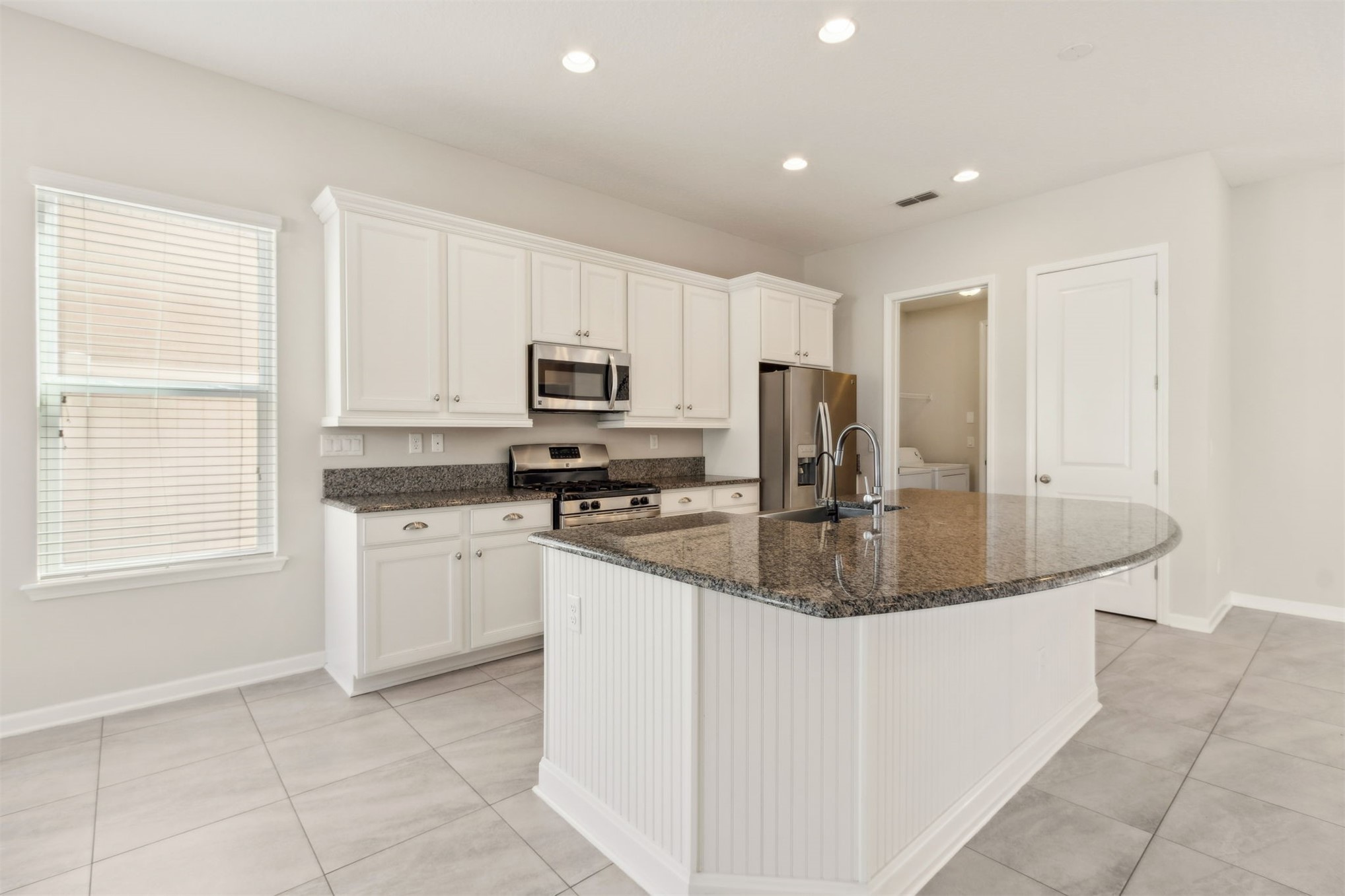 461 Sargasso Street Fernandina Beach, FL 32034 - Photo 5 of 40 a kitchen with kitchen island granite countertop a sink a stove a microwave a counter top space and cabinets