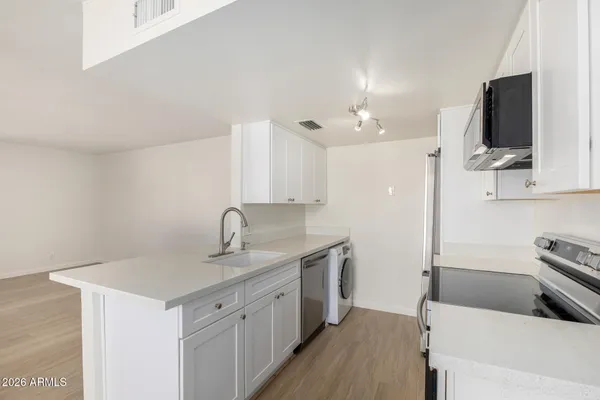 a kitchen with a sink dishwasher and a stove with wooden floor