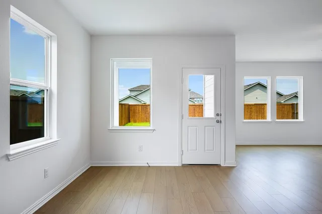 a view of an empty room with window and wooden floor