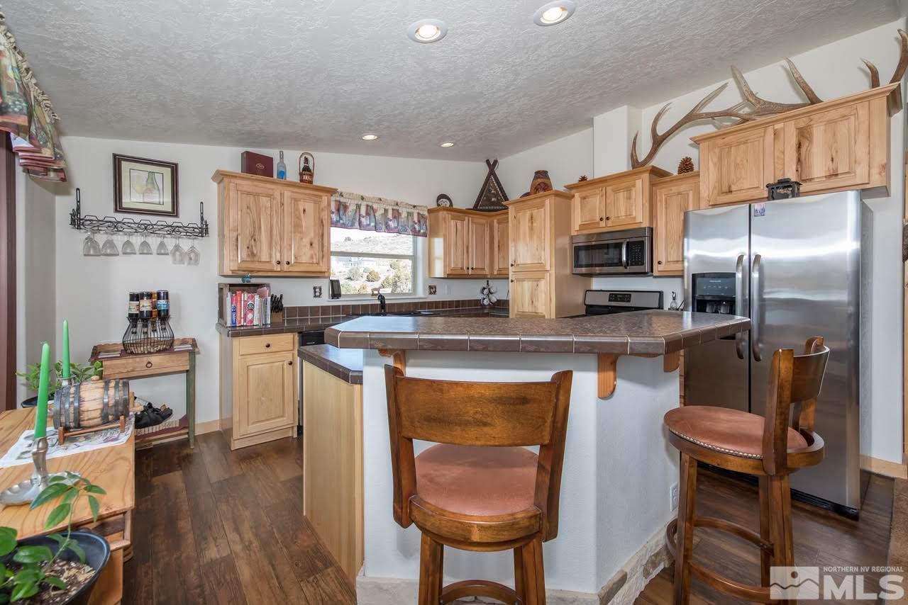 3230 Cartwright Road Reno, NV 89521 - Photo 14 of 25 a kitchen with stainless steel appliances kitchen island granite countertop a refrigerator a stove a sink a dining table and chairs with wooden floor