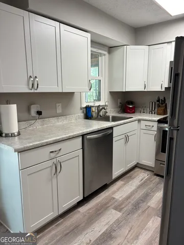 a kitchen with a sink white cabinets and white appliances