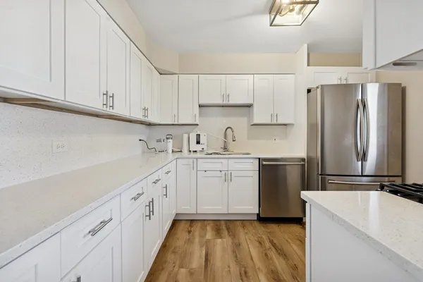 a kitchen with granite countertop a sink stainless steel appliances and white cabinets