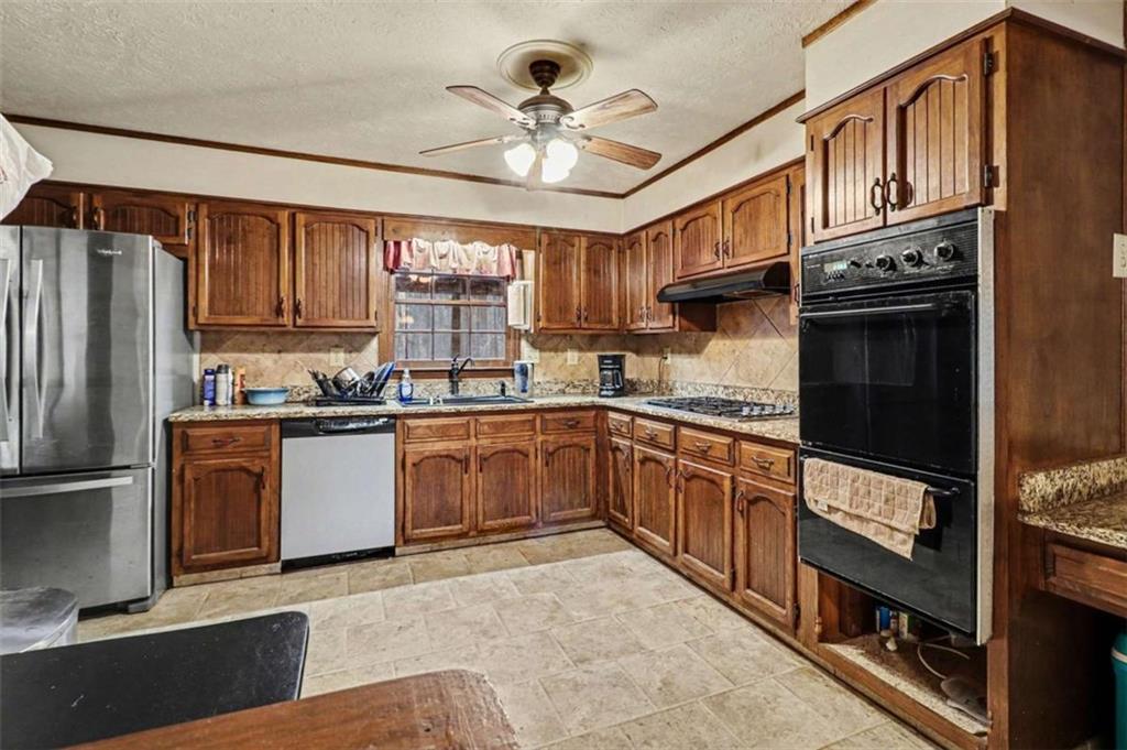 7495 Phillips Road Chattahoochee Hills, GA 30268 - Photo 7 of 26 a kitchen with granite countertop a refrigerator stove top oven a sink and dishwasher