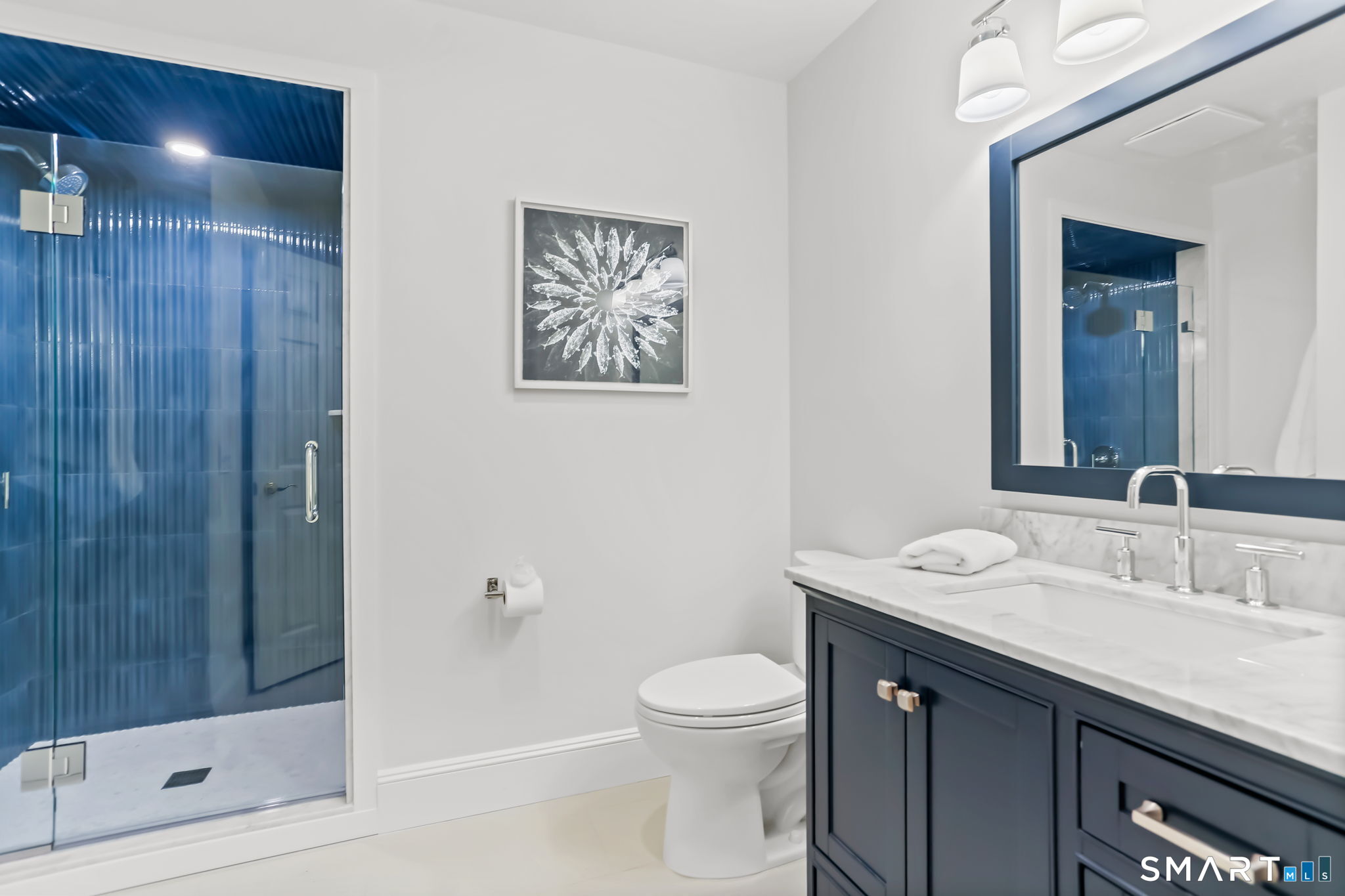 1149 Fairfield Beach Road Fairfield, CT 06824 - Photo 18 of 44 Newly updated main level full bath w/ shower tiled in a beautiful beachy blue vertical w/ glass door and complimentary navy blue vanity . Great for rinsing off the sand before entering main home