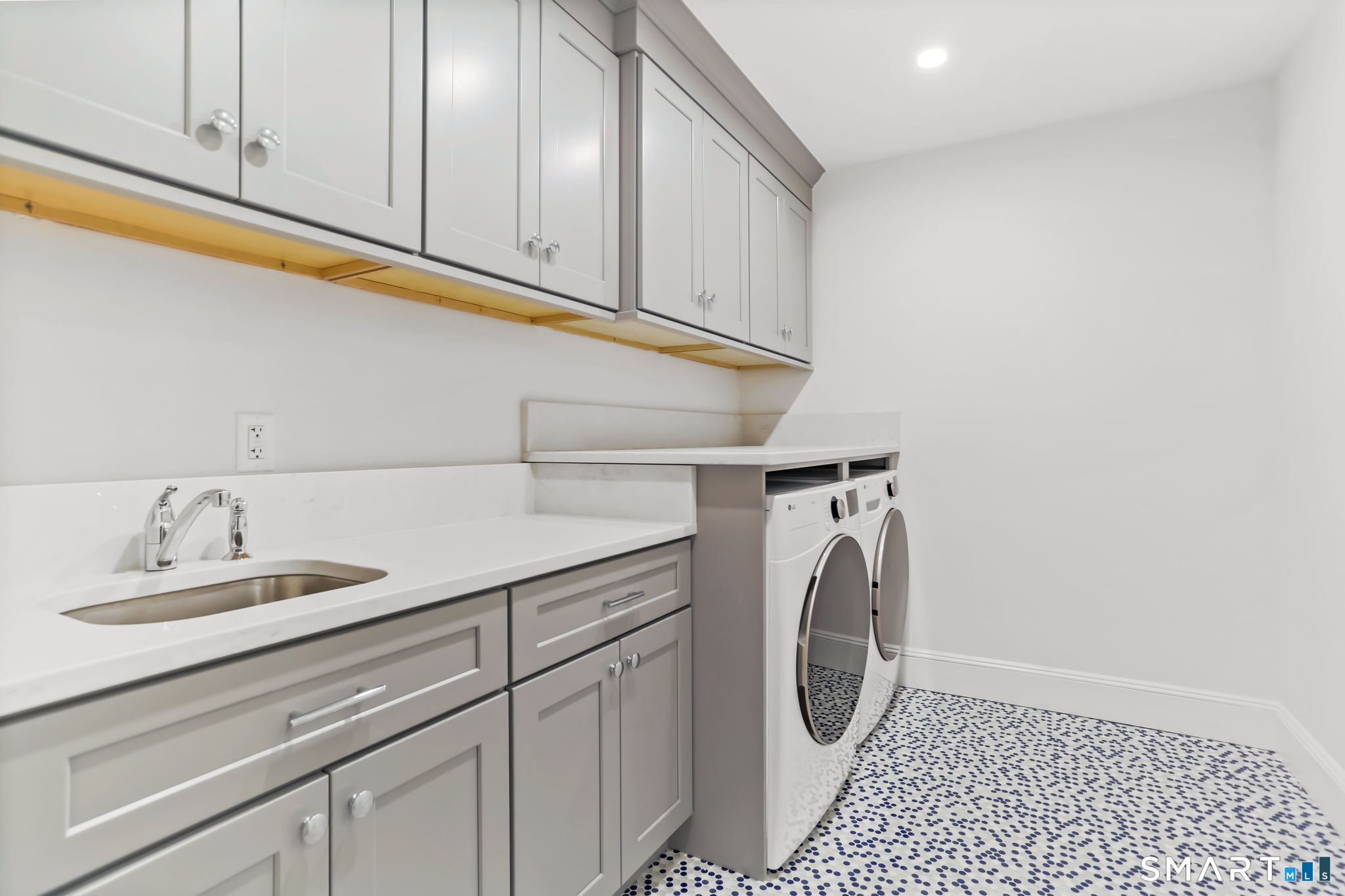 1149 Fairfield Beach Road Fairfield, CT 06824 - Photo 19 of 44 Newly updated laundry w/fun penny tiles in navy white and glass. Wall of upper and lower cabinets in a complementary grey provide so much storage and great space for folding