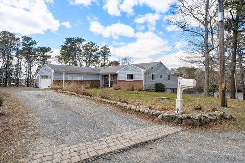 a front view of a house with a dirt yard and a large tree