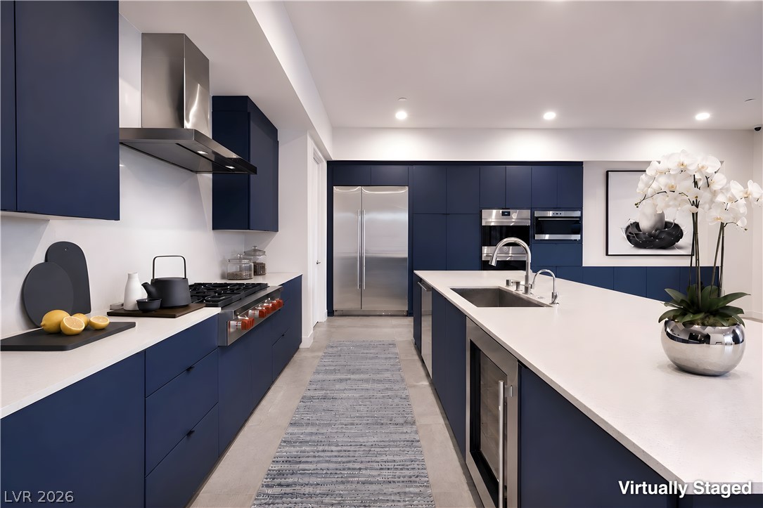 25 Falling Ridge Lane Henderson, NV 89011 - Photo 9 of 48 Modern kitchen with deep blue cabinetry and white countertops, featuring stainless steel appliances.