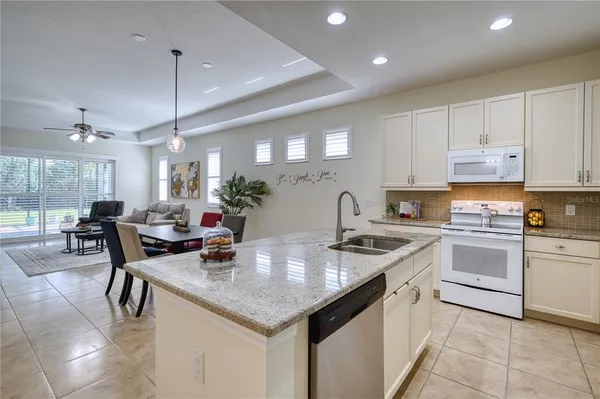 a kitchen with stainless steel appliances granite countertop table chairs sink and cabinets