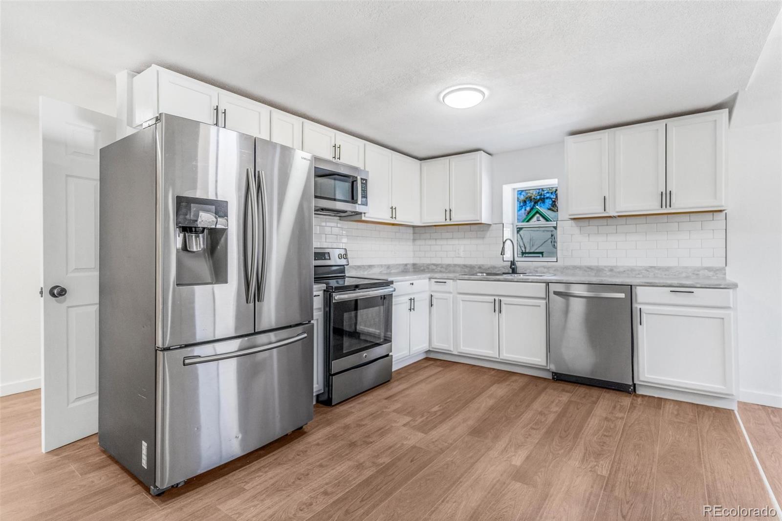 350 South Elbert Street Elizabeth, CO 80107 - Photo 18 of 22 a kitchen with white cabinets stainless steel appliances and wooden floor