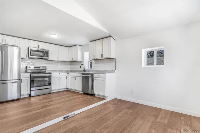 a kitchen with granite countertop white cabinets and stainless steel appliances