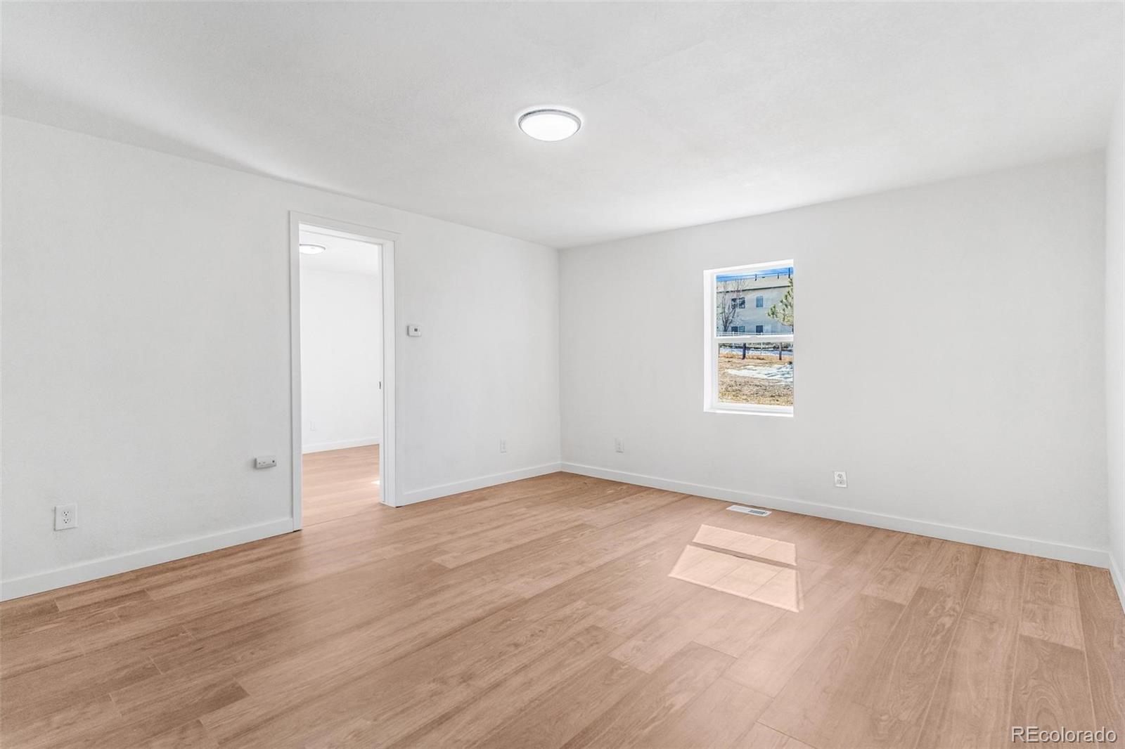 350 South Elbert Street Elizabeth, CO 80107 - Photo 5 of 22 an empty room with wooden floor and windows