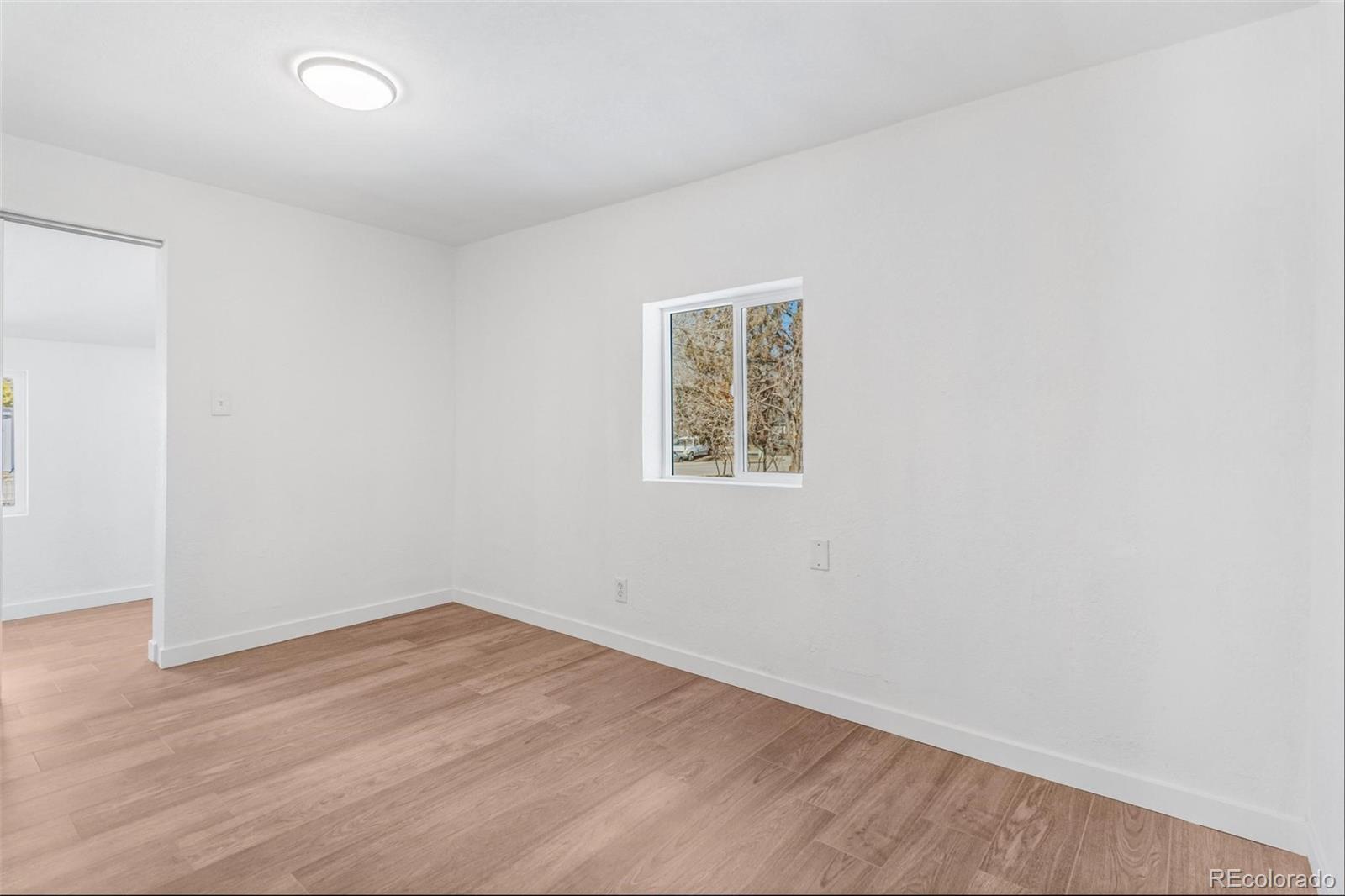 350 South Elbert Street Elizabeth, CO 80107 - Photo 8 of 22 an empty room with wooden floor and windows