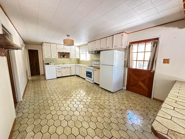 a kitchen with a refrigerator and white cabinets