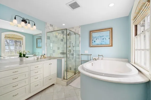 a spacious bathroom with a tub sink and mirror