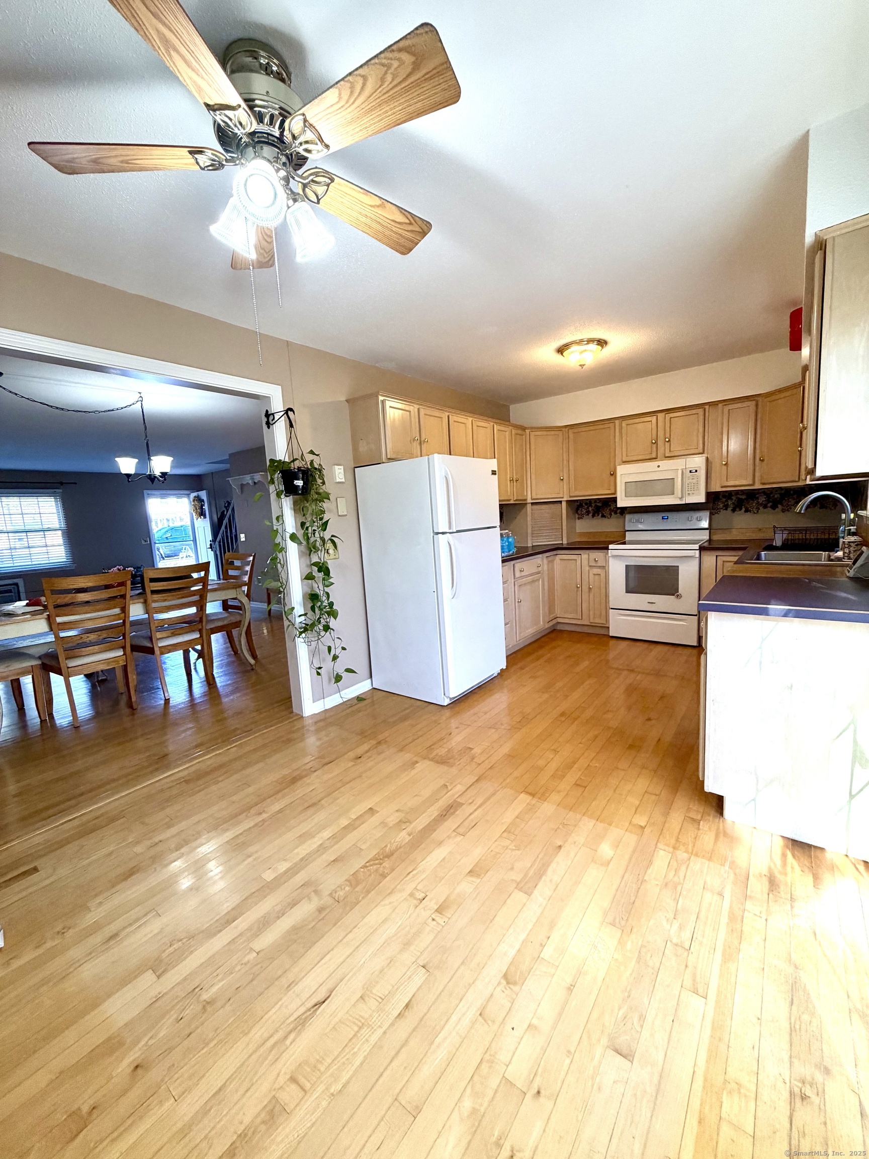 a kitchen with stainless steel appliances kitchen island granite countertop a table chairs and a refrigerator