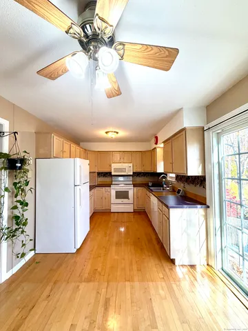 a large white kitchen with a large window a refrigerator and stainless steel appliances