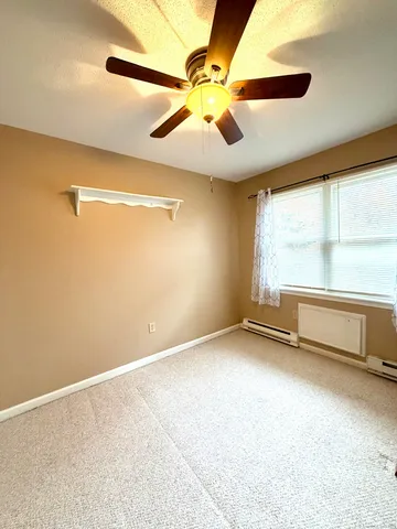 an empty room with windows and fan