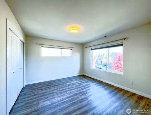 a view of an empty room with a window and wooden floor