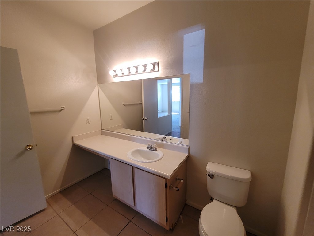 7413 West Russell Road, Unit 107 Las Vegas, NV 89113 - Photo 15 of 48 Half bath with tile patterned flooring, toilet, vanity, and baseboards