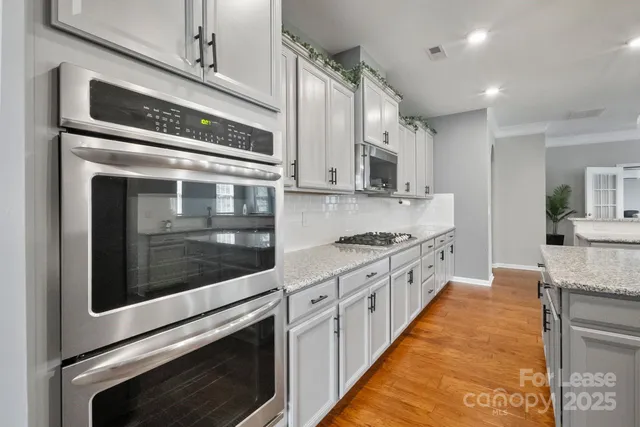 a large kitchen with stainless steel appliances granite countertop a stove and a sink
