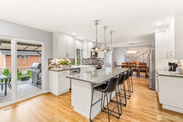 a kitchen with stainless steel appliances kitchen island granite countertop a table chairs and a view of living room