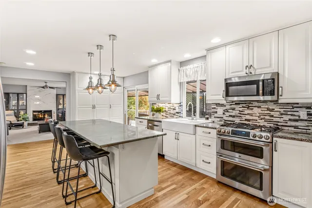 a kitchen with stainless steel appliances kitchen island granite countertop a stove a sink and a refrigerator