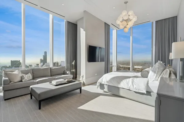 a spacious bedroom with a bed a couch and a chandelier
