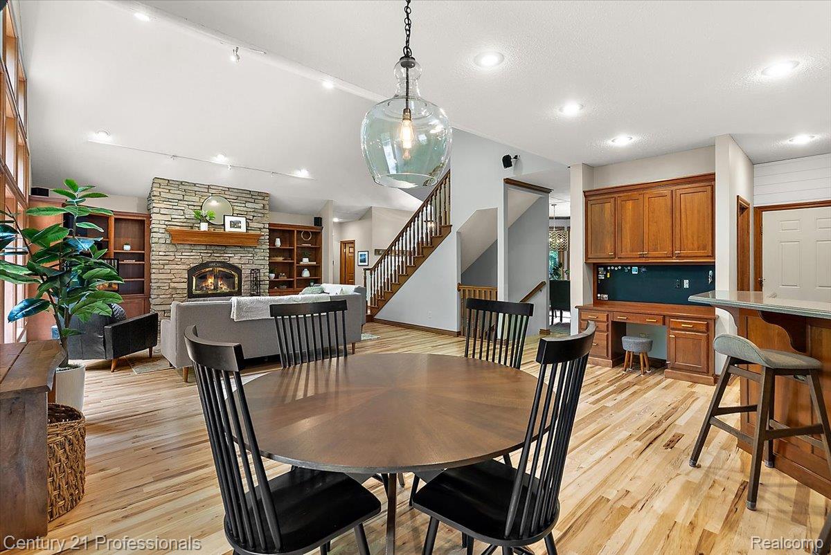 9867 Rainbow Ridge Drive Schoolcraft, MI 49087 - Photo 21 of 82 Open-concept living space with wood-finish flooring, a stone-surround fireplace with a wood mantle, built-in shelving, a built-in desk area with wood cabinetry, and a staircase with wood railing