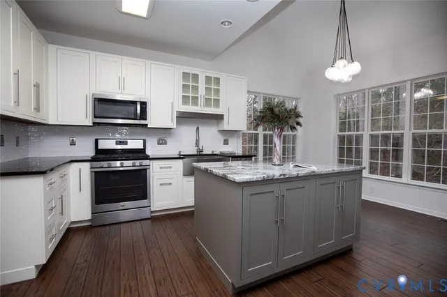 a kitchen with granite countertop stainless steel appliances a stove a sink a window and cabinets