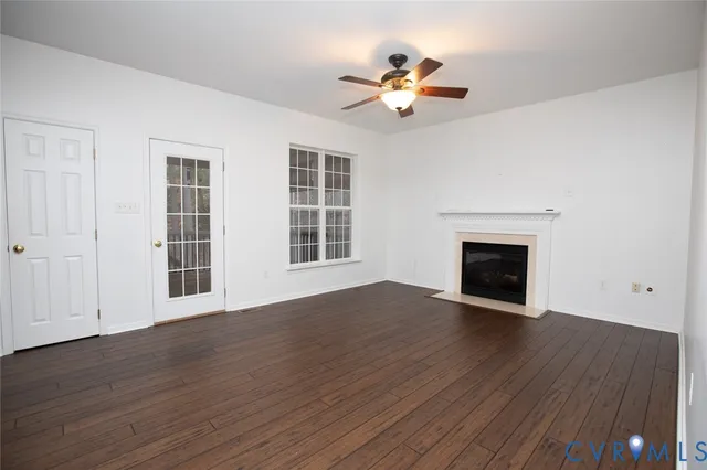 a view of an empty room with wooden floor fireplace and a window