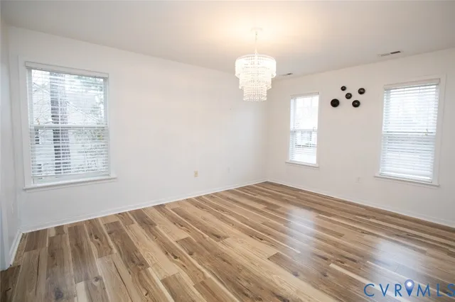 a view of empty room with wooden floor and window