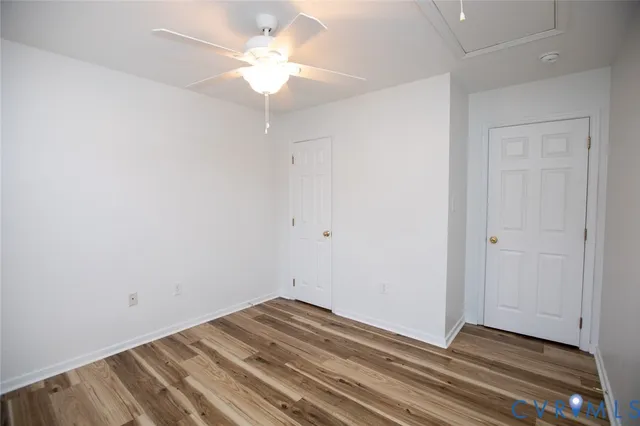 a view of a room with wooden floor and a ceiling fan