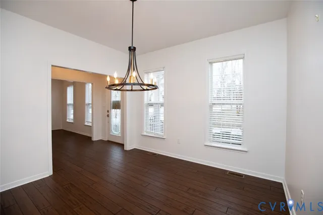 a view of an empty room with wooden floor fridge and a window