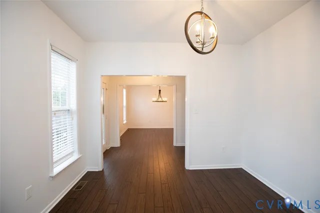 an empty room with wooden floor a mirror and a window