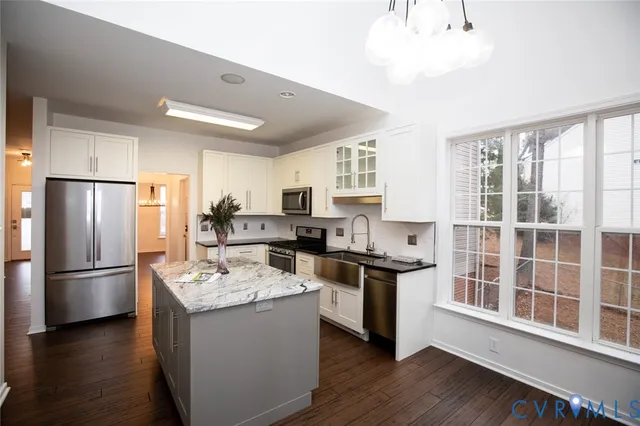 a kitchen with stainless steel appliances granite countertop a refrigerator a sink dishwasher a stove and a refrigerator with wooden floor